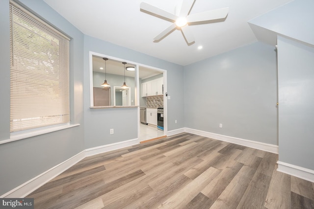 unfurnished living room featuring plenty of natural light, ceiling fan, and light hardwood / wood-style flooring