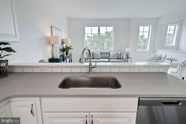 kitchen featuring white cabinetry, stainless steel dishwasher, kitchen peninsula, and sink