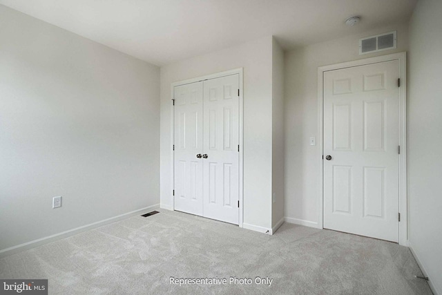 unfurnished bedroom with light colored carpet and a closet