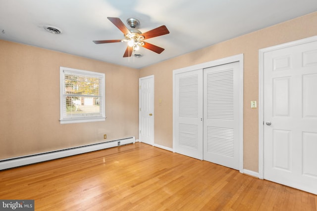 unfurnished bedroom featuring baseboard heating, hardwood / wood-style flooring, and ceiling fan