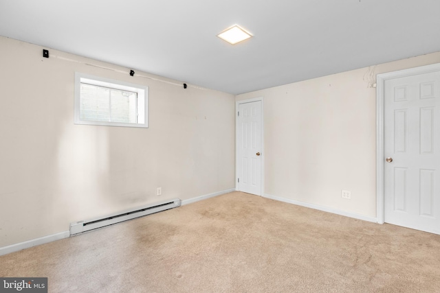 spare room featuring baseboard heating and light colored carpet