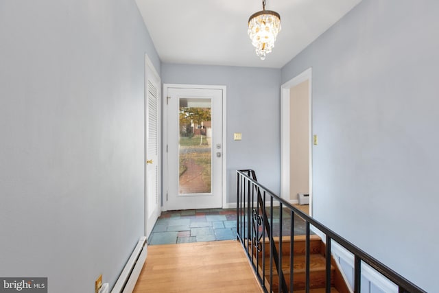 doorway to outside with wood-type flooring, a notable chandelier, and a baseboard heating unit