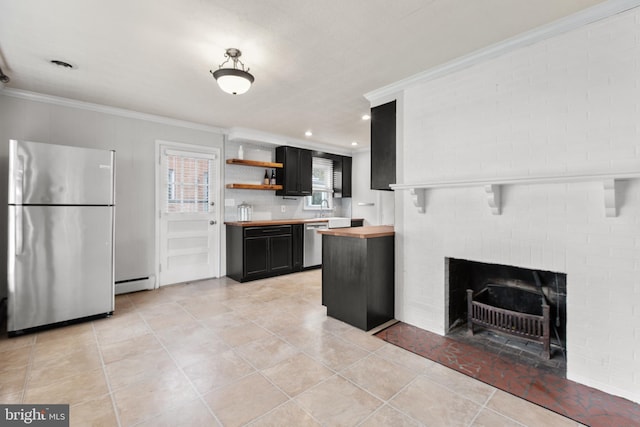 kitchen featuring butcher block countertops, a brick fireplace, crown molding, and stainless steel appliances