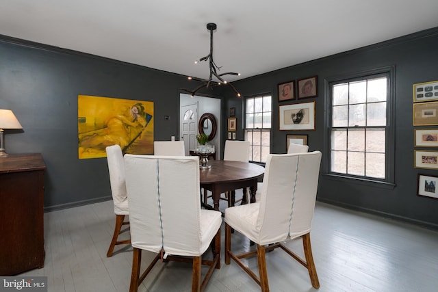 dining room featuring ornamental molding, a notable chandelier, baseboards, and hardwood / wood-style flooring