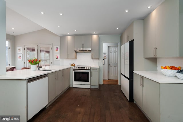 kitchen with light countertops, a sink, white appliances, a peninsula, and under cabinet range hood