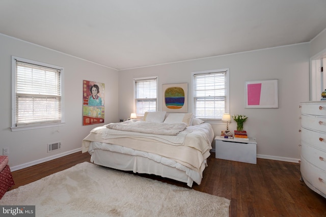 bedroom with visible vents, baseboards, and wood finished floors