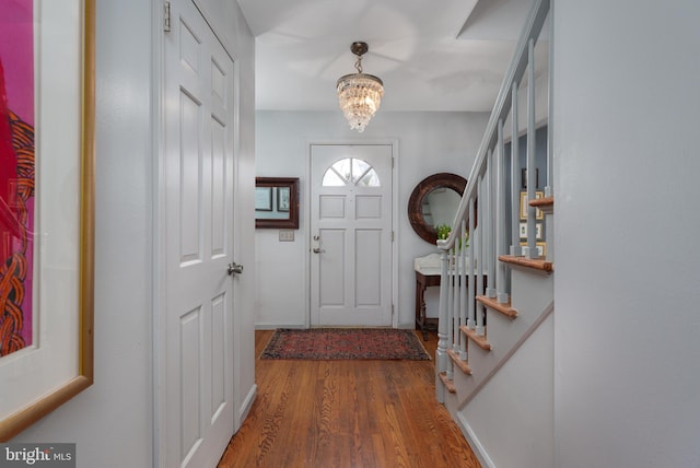 entryway featuring a chandelier, stairway, and wood finished floors