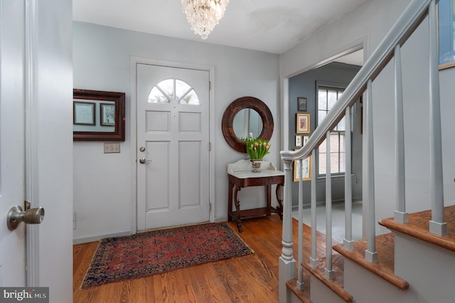 entrance foyer featuring an inviting chandelier, baseboards, stairway, and wood finished floors