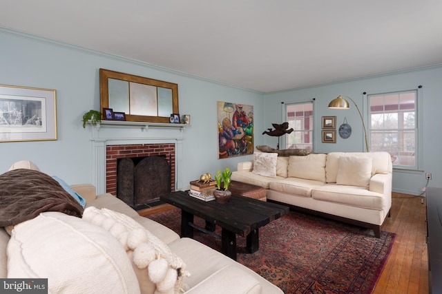 living room featuring ornamental molding, a brick fireplace, and hardwood / wood-style flooring