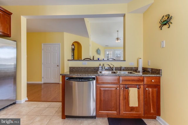 kitchen with ceiling fan, sink, stainless steel appliances, dark stone counters, and light tile patterned flooring