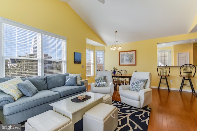 living room featuring vaulted ceiling, plenty of natural light, a chandelier, and dark hardwood / wood-style floors