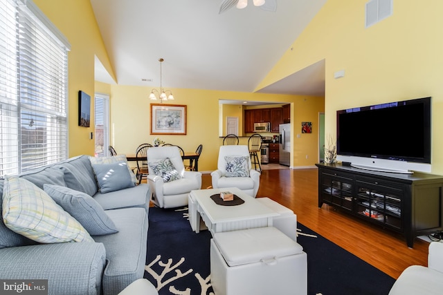 living room featuring a chandelier, hardwood / wood-style floors, and high vaulted ceiling