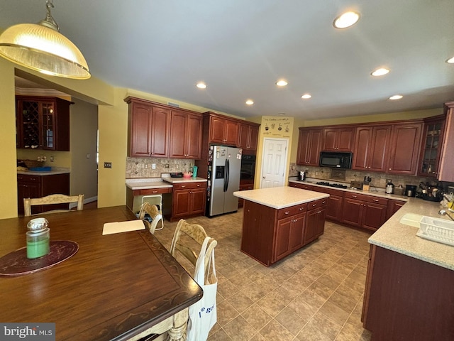 kitchen featuring hanging light fixtures, black appliances, tasteful backsplash, sink, and a kitchen island