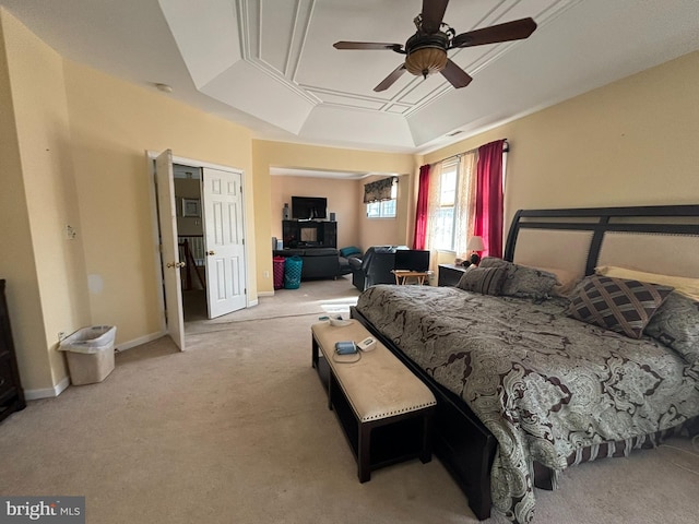 bedroom featuring light colored carpet, ceiling fan, a closet, and a tray ceiling