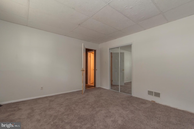 carpeted spare room featuring a drop ceiling