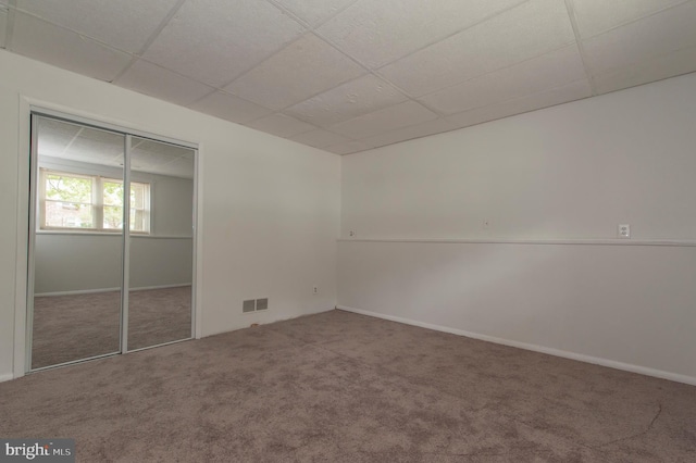 unfurnished bedroom featuring carpet flooring, a paneled ceiling, and a closet