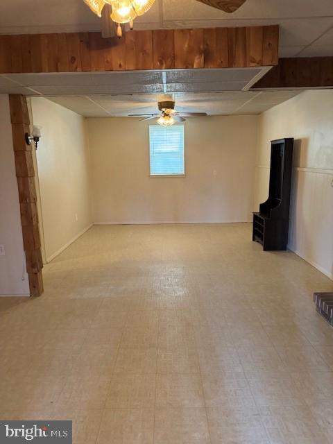 basement featuring ceiling fan and a drop ceiling