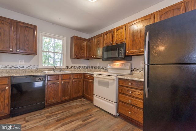 kitchen with light stone countertops, sink, dark hardwood / wood-style floors, and black appliances