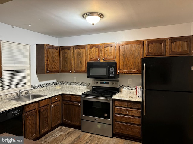 kitchen with black appliances, sink, and light hardwood / wood-style flooring