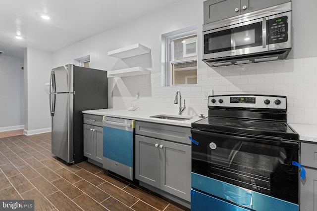 kitchen featuring stainless steel appliances, backsplash, gray cabinets, dark hardwood / wood-style flooring, and sink