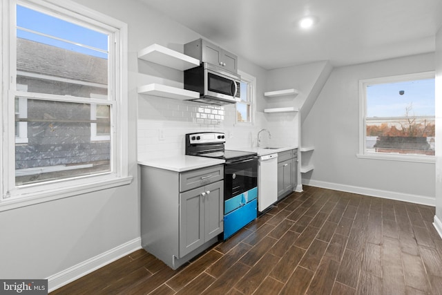 kitchen with gray cabinets, stainless steel appliances, dark hardwood / wood-style floors, and tasteful backsplash