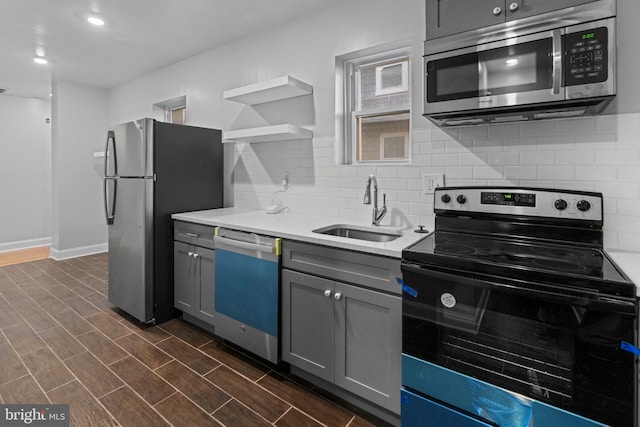 kitchen with sink, appliances with stainless steel finishes, dark hardwood / wood-style floors, gray cabinetry, and decorative backsplash