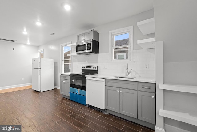 kitchen featuring dark hardwood / wood-style flooring, sink, gray cabinetry, backsplash, and white appliances