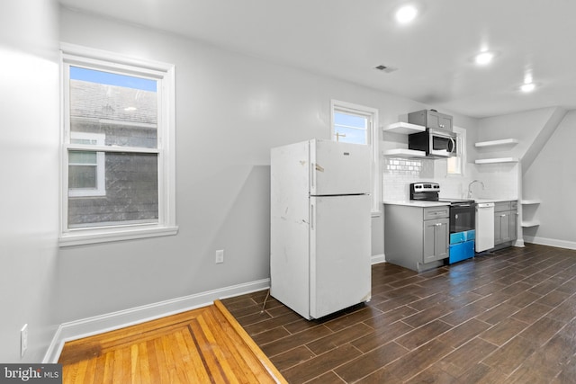 kitchen featuring white appliances, dark hardwood / wood-style floors, gray cabinetry, and backsplash