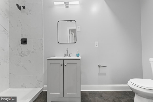 bathroom featuring toilet, vanity, tile patterned floors, and tiled shower