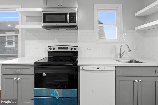 kitchen with gray cabinetry, tasteful backsplash, sink, and stainless steel appliances