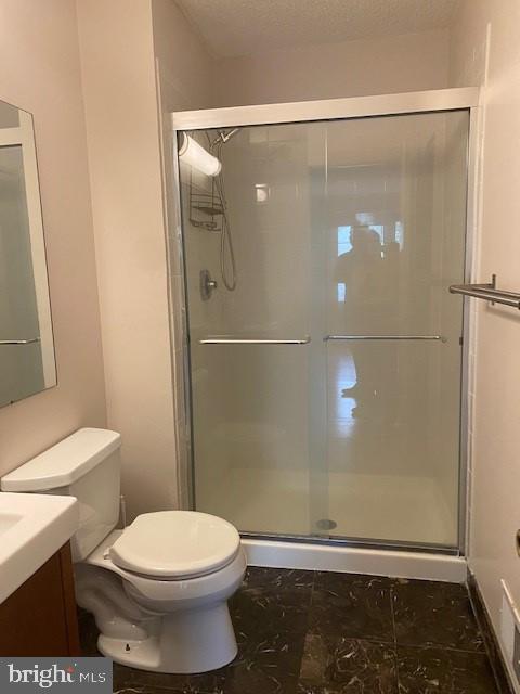 bathroom featuring an enclosed shower, vanity, a textured ceiling, and toilet