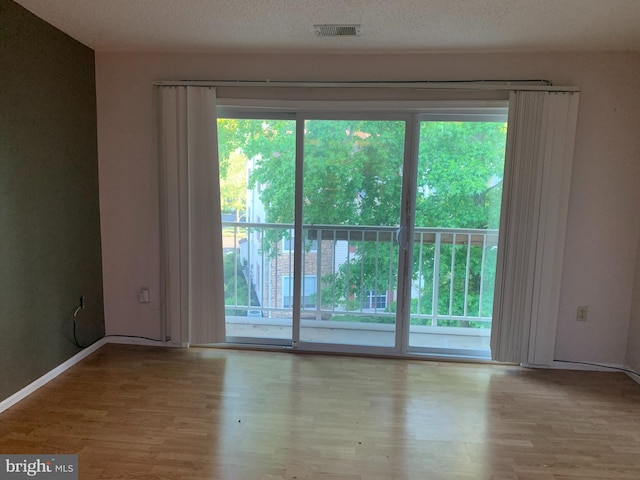 spare room featuring light wood-type flooring and a textured ceiling