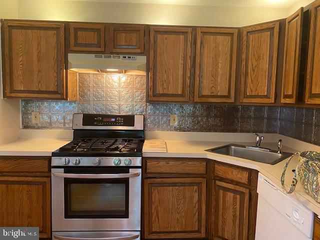 kitchen with sink, white dishwasher, stainless steel range with gas cooktop, and backsplash