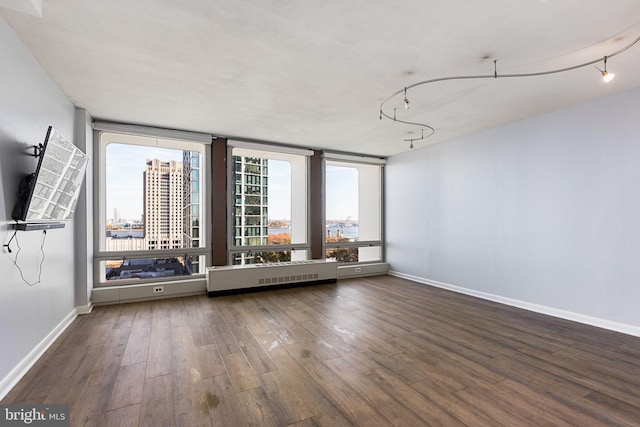 empty room featuring dark hardwood / wood-style flooring and rail lighting