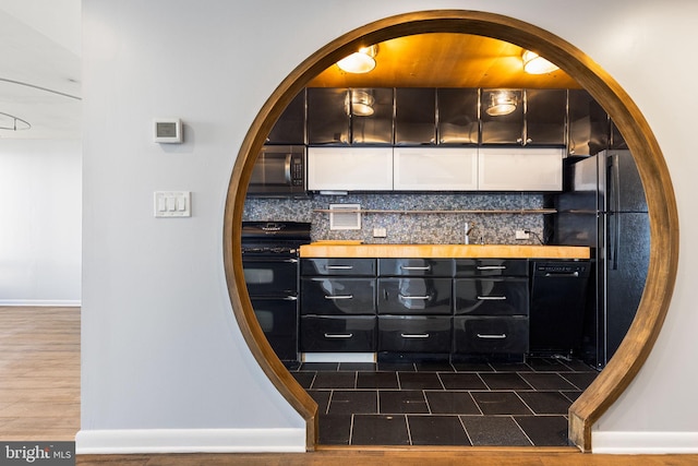 bar featuring dark hardwood / wood-style floors, black appliances, and decorative backsplash