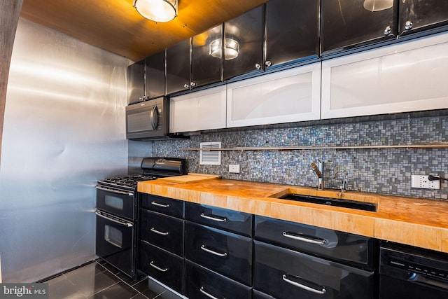 kitchen featuring black appliances, dark tile patterned floors, backsplash, wood counters, and sink