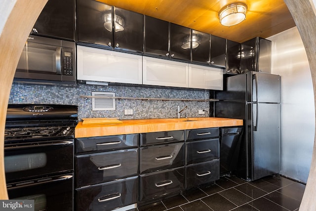 kitchen with black appliances, backsplash, and wood counters