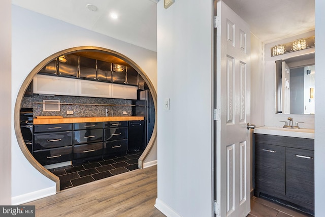 bathroom featuring wood-type flooring, backsplash, and vanity