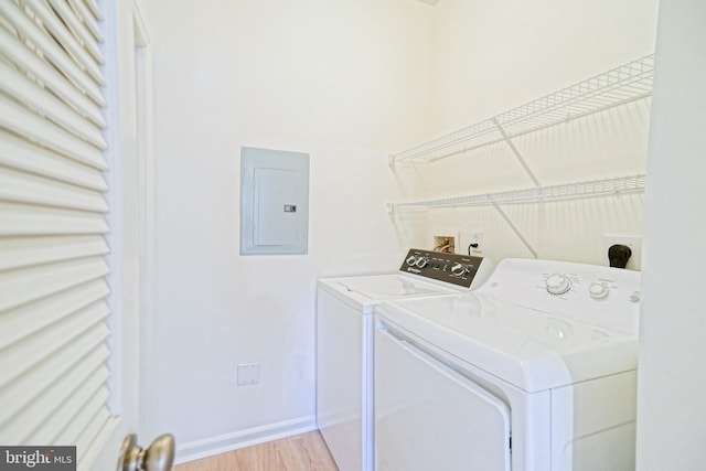 washroom with electric panel, light hardwood / wood-style floors, and washing machine and dryer