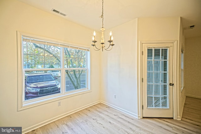 unfurnished dining area with light hardwood / wood-style floors and a notable chandelier