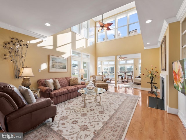 living room with ornamental molding, ceiling fan, and light hardwood / wood-style floors