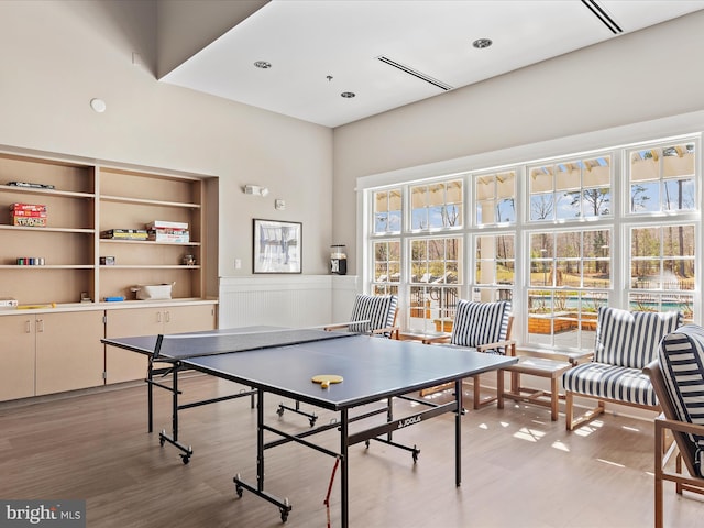 game room with a high ceiling and light wood-type flooring