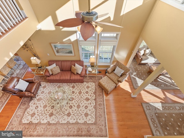 living room with hardwood / wood-style floors, a towering ceiling, and ceiling fan