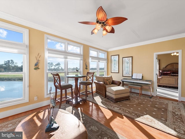 sitting room featuring hardwood / wood-style floors, a water view, ceiling fan, and crown molding