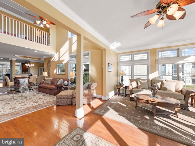 living room with ornamental molding, a healthy amount of sunlight, ceiling fan with notable chandelier, and wood-type flooring