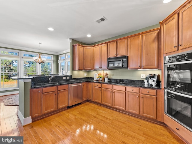 kitchen featuring pendant lighting, dark stone counters, black appliances, light hardwood / wood-style floors, and a chandelier