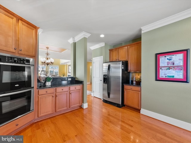 kitchen featuring appliances with stainless steel finishes, ornamental molding, dark stone countertops, a chandelier, and light hardwood / wood-style floors