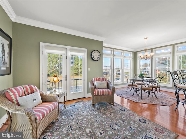 living room with ornamental molding, a healthy amount of sunlight, a notable chandelier, and wood-type flooring