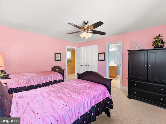 carpeted bedroom with ensuite bathroom, a closet, and ceiling fan