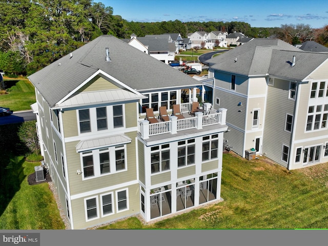 rear view of property with a yard, a balcony, and central air condition unit